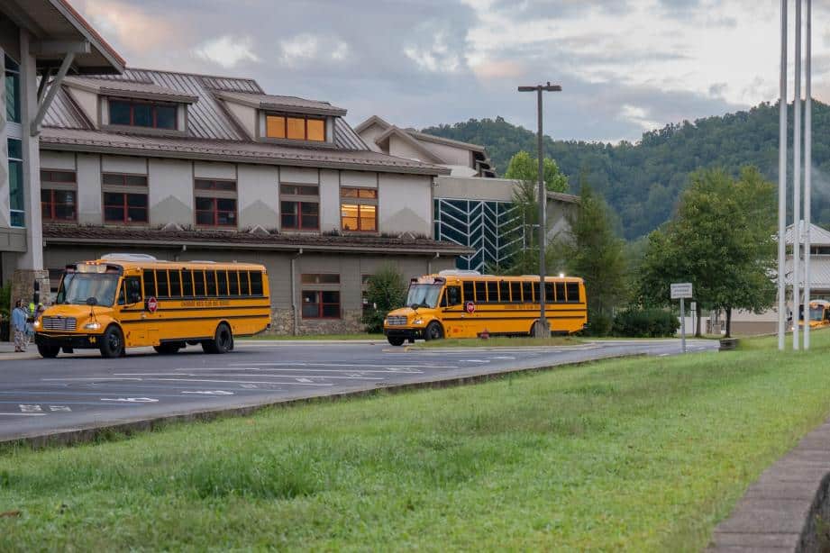 two electric school buses in front of a school