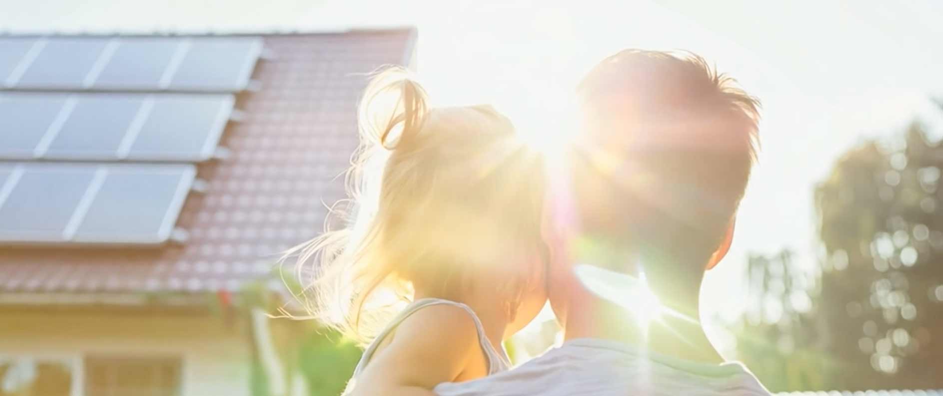 Father holding his daughter as sun rises in the background