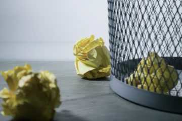 Image shows crumpled paper in a trash bin